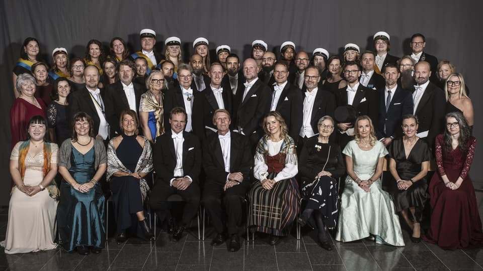 A group photo of just over fifty well-dressed people.