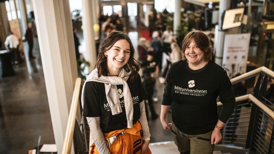 Två glada, kvinnliga studenter som står på trappan i Ljushallen