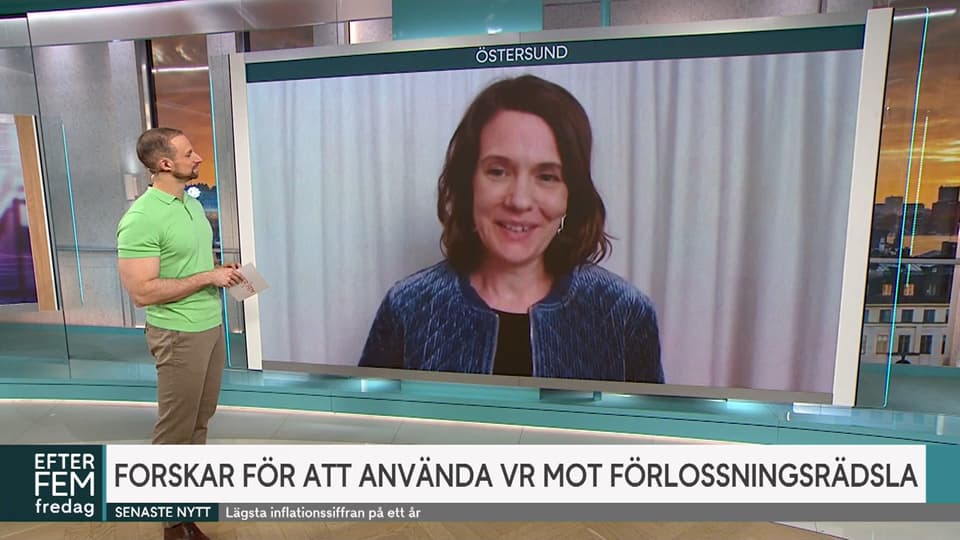Man står framför en stor bildskärm och intervjuar en kvinna som medverkar via länk