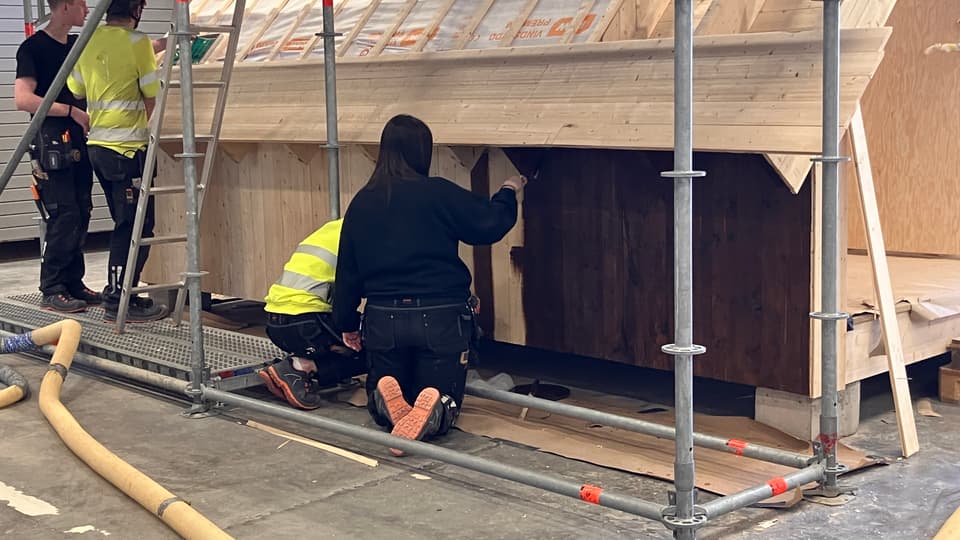 byggnadsställningar, en pågående byggnad och några personer sittande på huk
