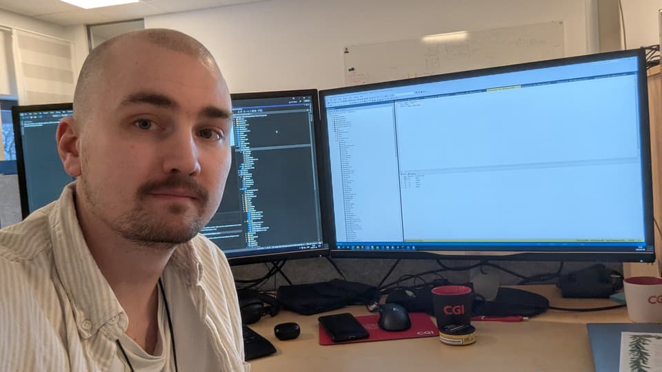 En man sitter framför två dataskärmar.