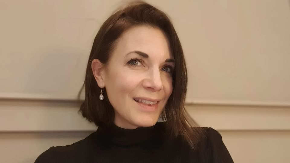 A woman looks into the camera and smiles.