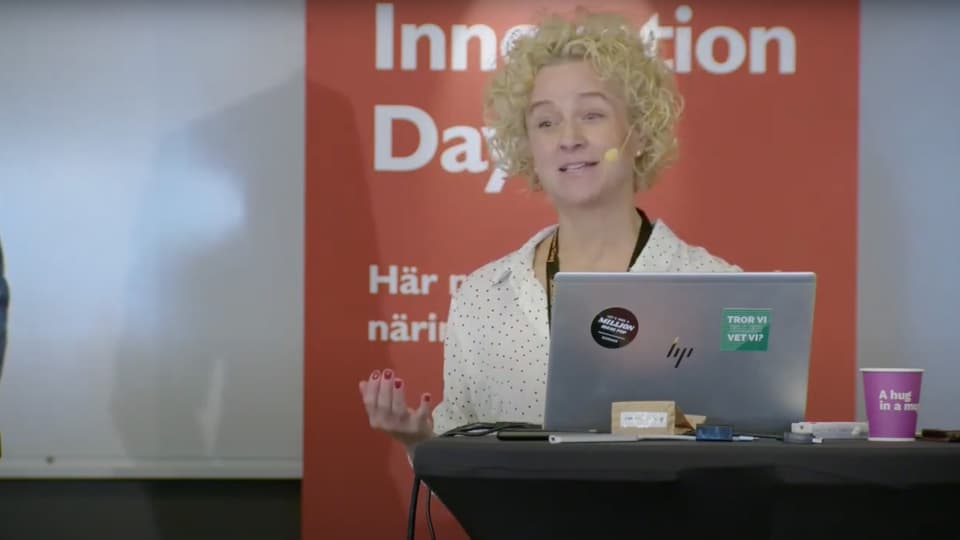 En kvinna föreläser med en laptop framför sig
