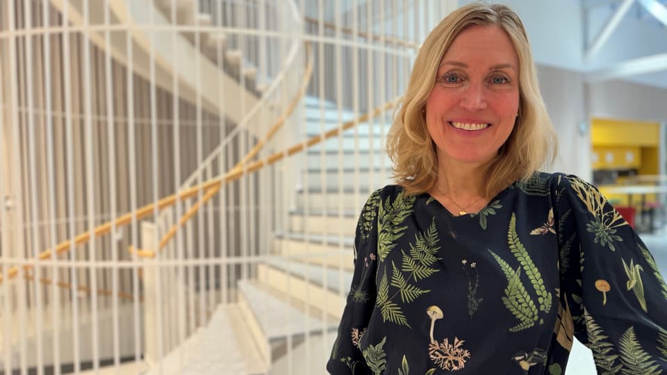 Leende kvinna i en svart klänning med gröna blommor