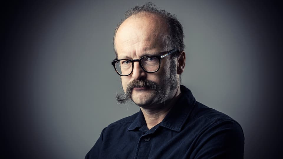 Portrait photo of a man in a black shirt and black glasses