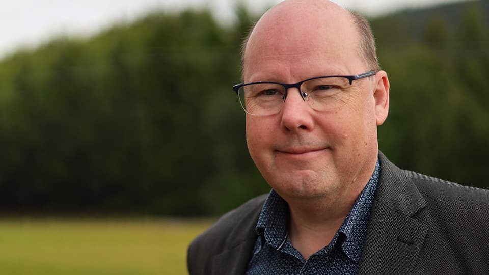 A man without hair and black glasses