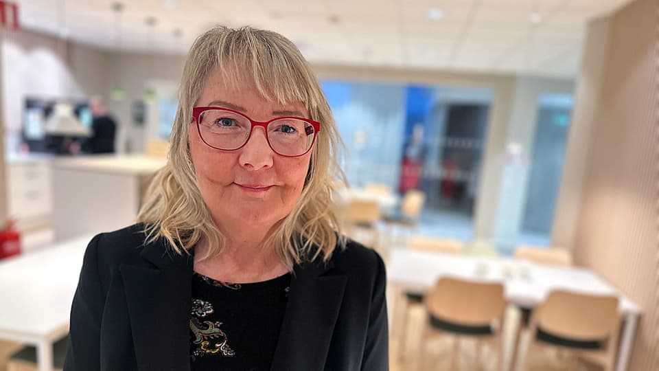 En kvinna med glasögon står i ett kök