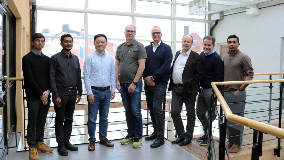 8 men stand lined up and smile at the camera