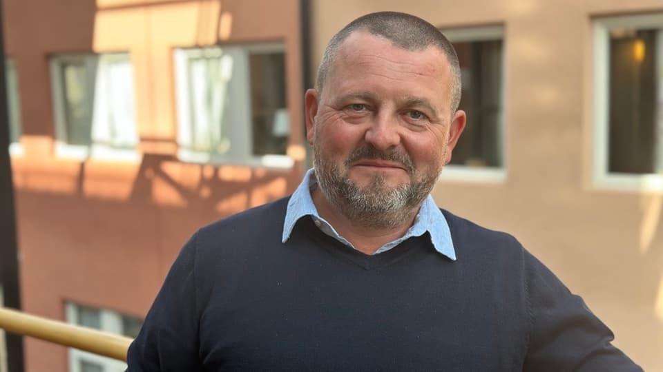 En man med snaggat mörkt hår och en mörkblå tröja