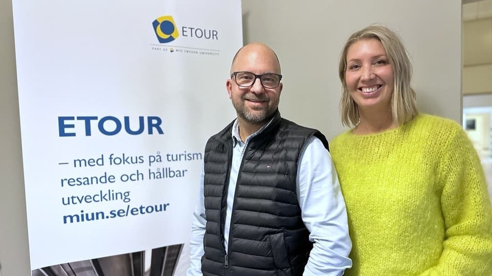 En man och en kvinna står framför en roll-up och ler