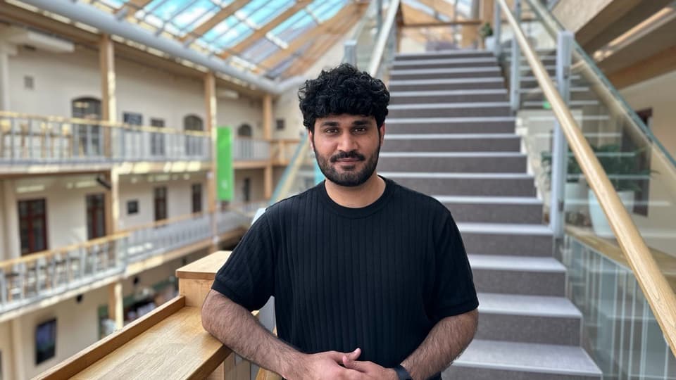 A man with short black hair and a black t-shirt