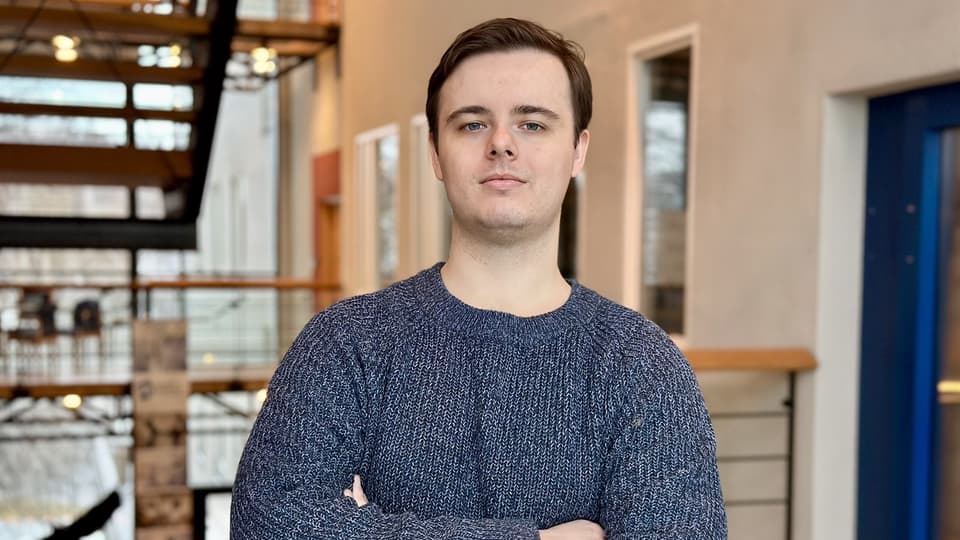 Young man in a dark blue sweater with brown hair.