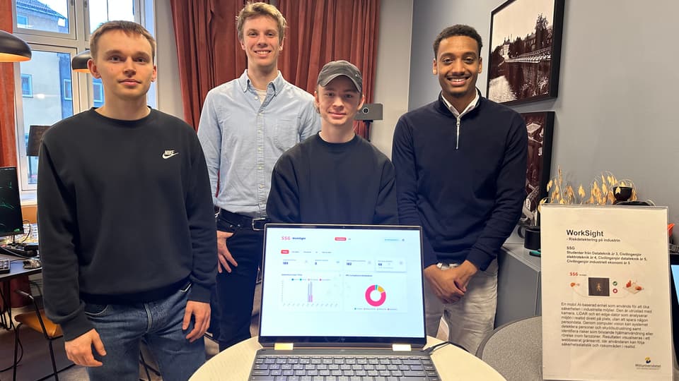 Four young men is standing behind a laptop