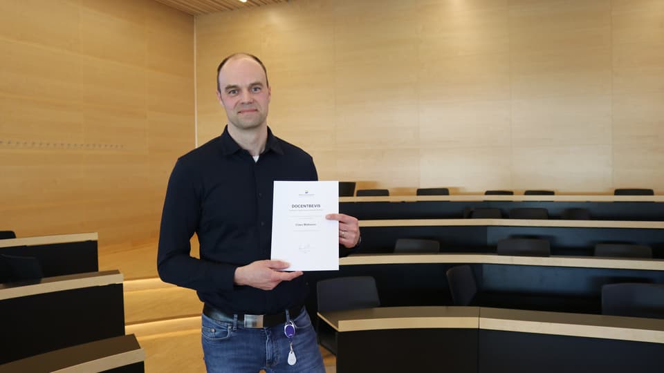 A person stands and presents an associate professor’s certificate.