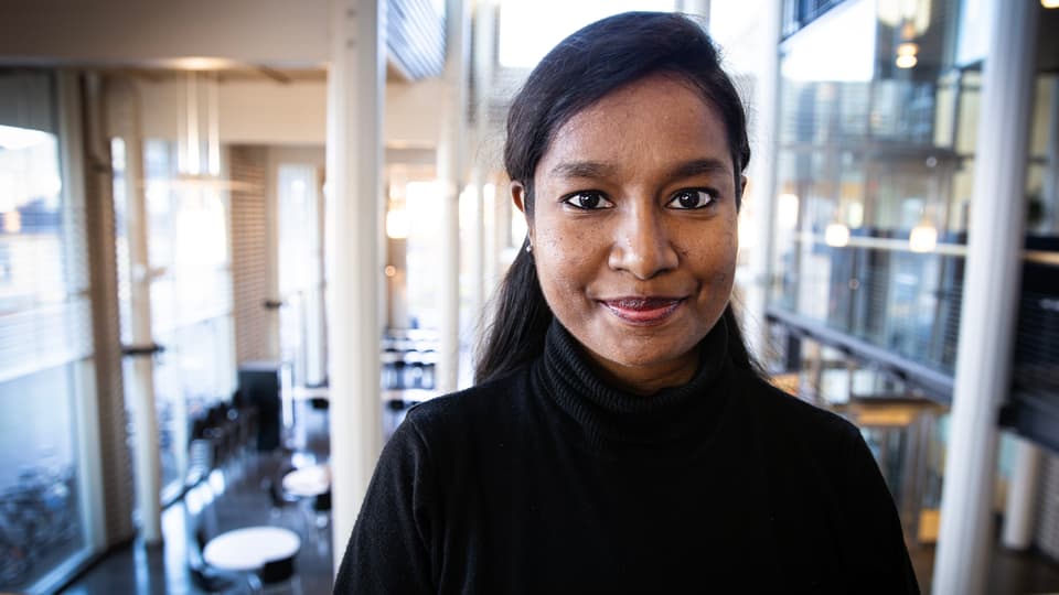 Woman in black shirt and with black hair looks at the camera.