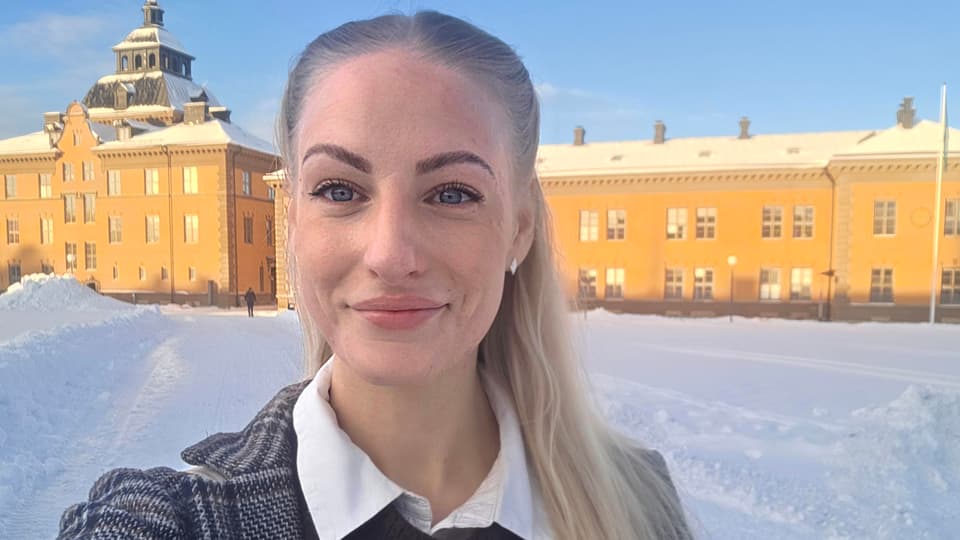 Utomhusbild av kvinna som står med byggnad i bakgrunden.