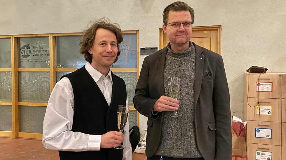 Two men toast in front of the camera.