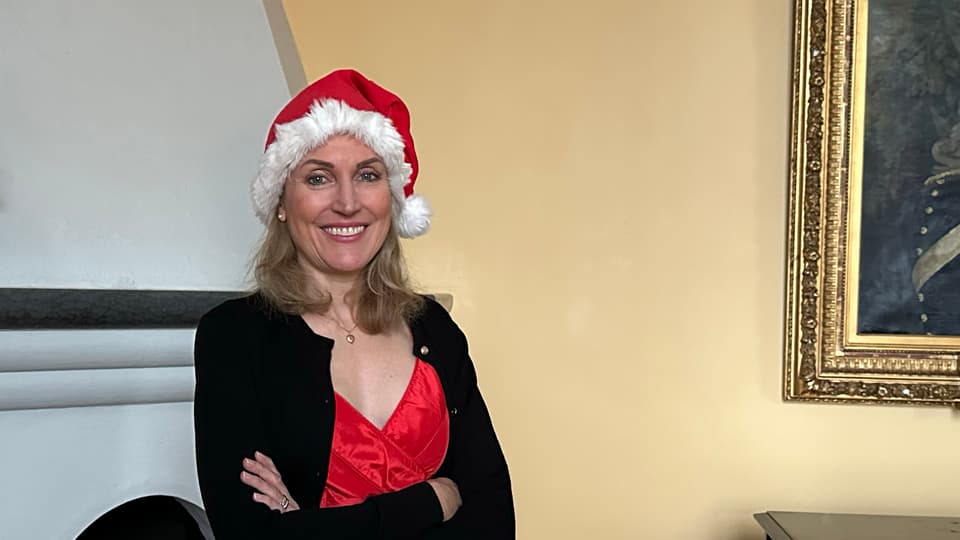 Woman in red dress, black jacket and Santa hat
