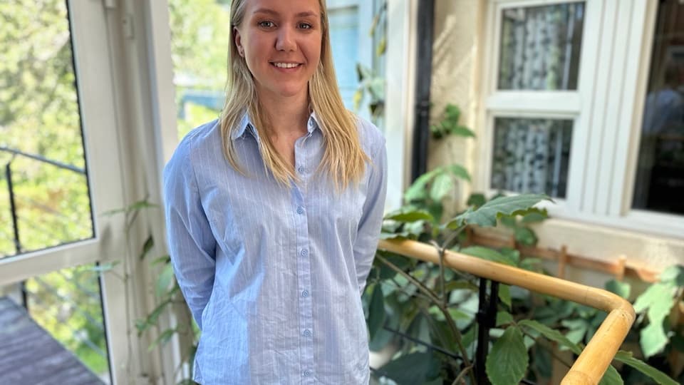 Porträtt av blonde tjej i vitrandigskjorts ståendes i ljushallen i en av campusbyggnaderna