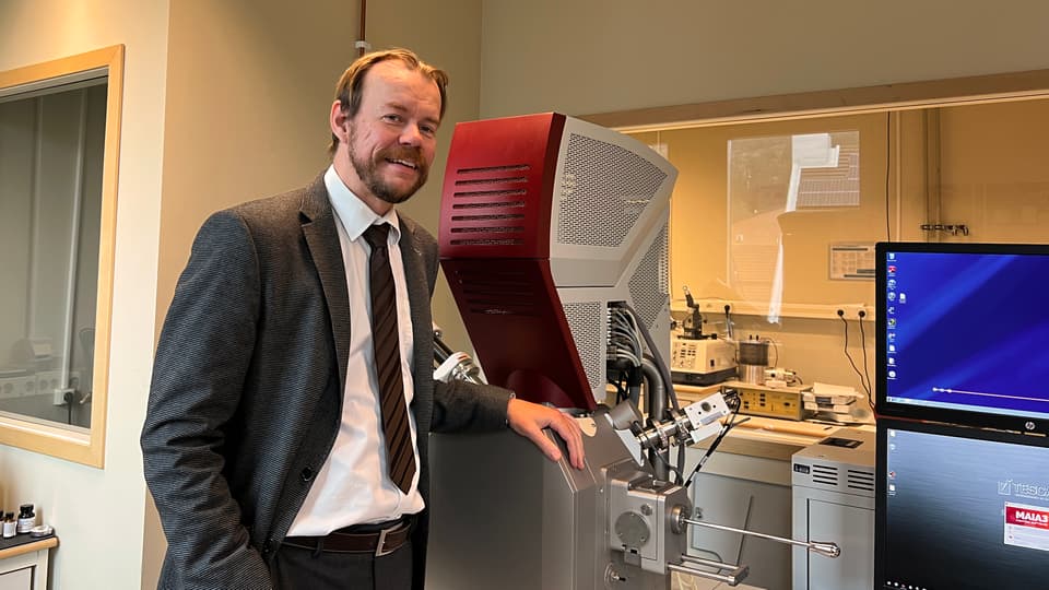  A man stands in front of laboratory equipment and monitors.