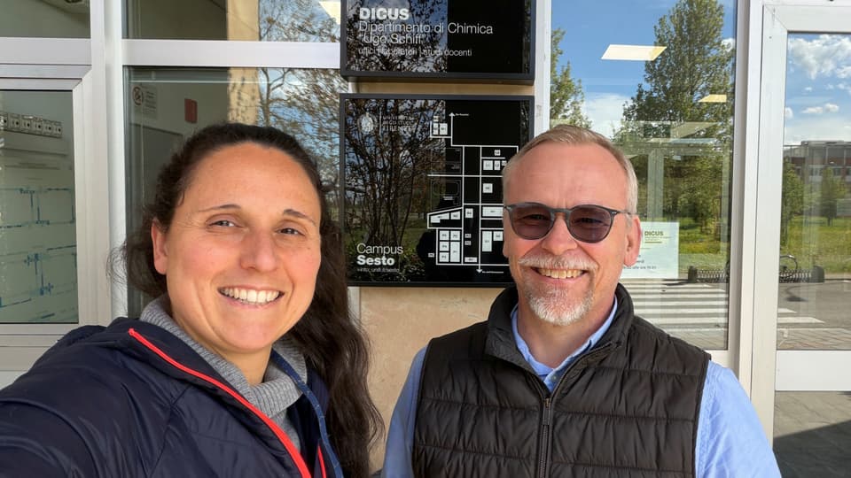 A woman and a man wearing sunglasses are smiling and looking into the camera.