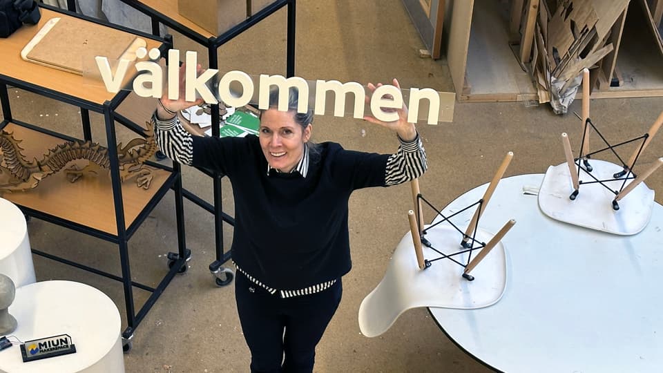 En kvinna håller en skult som det står välkommen på