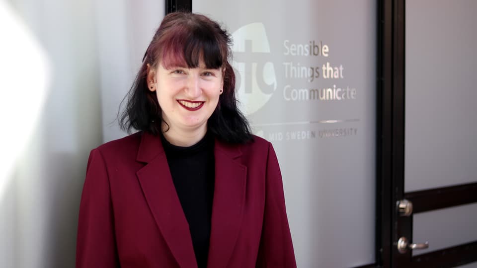 A woman in a dark red jacket smiles at the camera