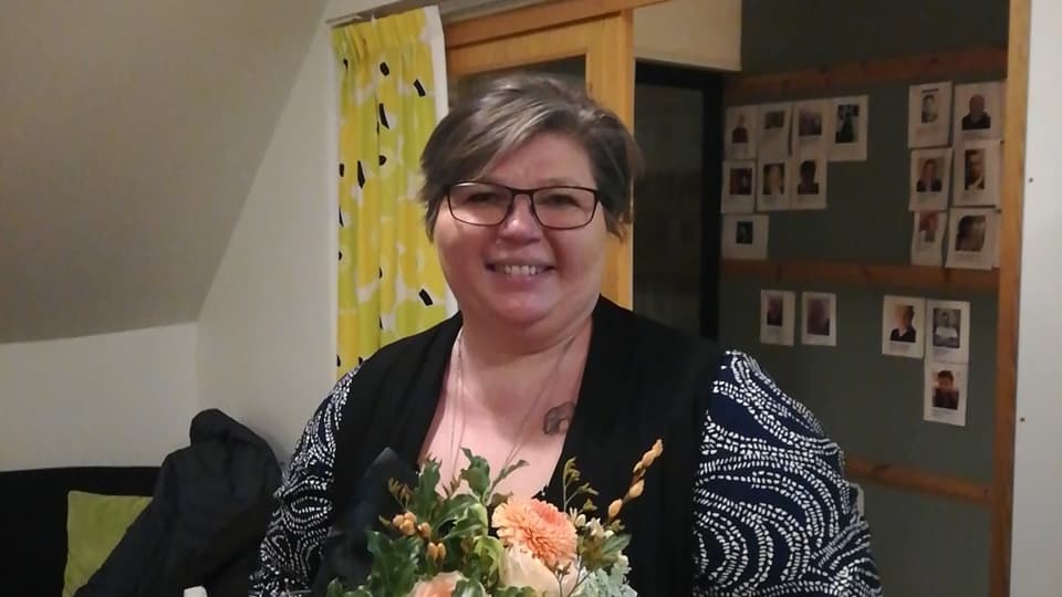Martina Granholm håller en blombukett i handen. Hon ser in i kameran och ler.