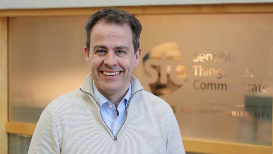 A man with dark hair and white sweater