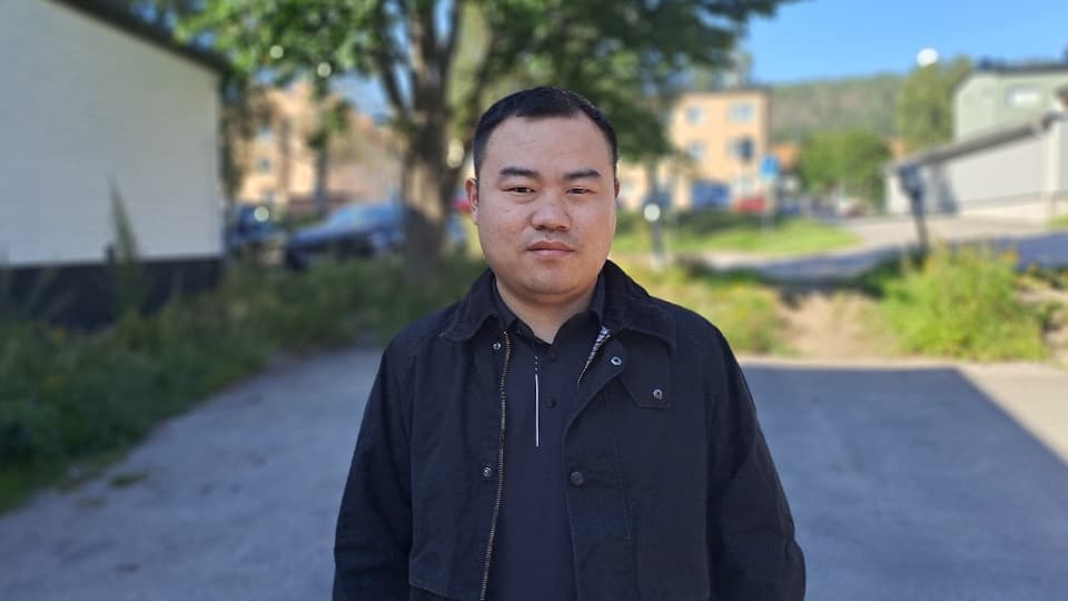 A man with a black jacket standing outside