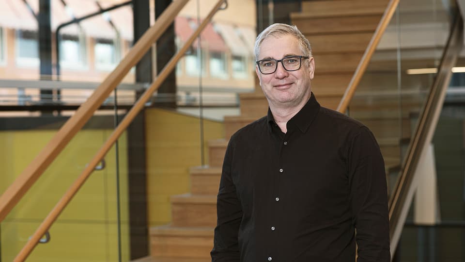 Man in black shirt in front of stairs