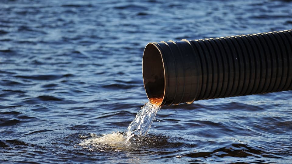 Water flowing out of a sewer pipe into a lake.