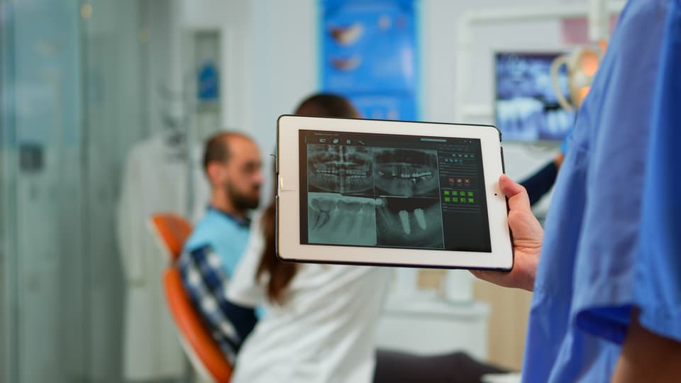 Närbild tandläkare sjuksköterska håller tablett med digitala tandbilder