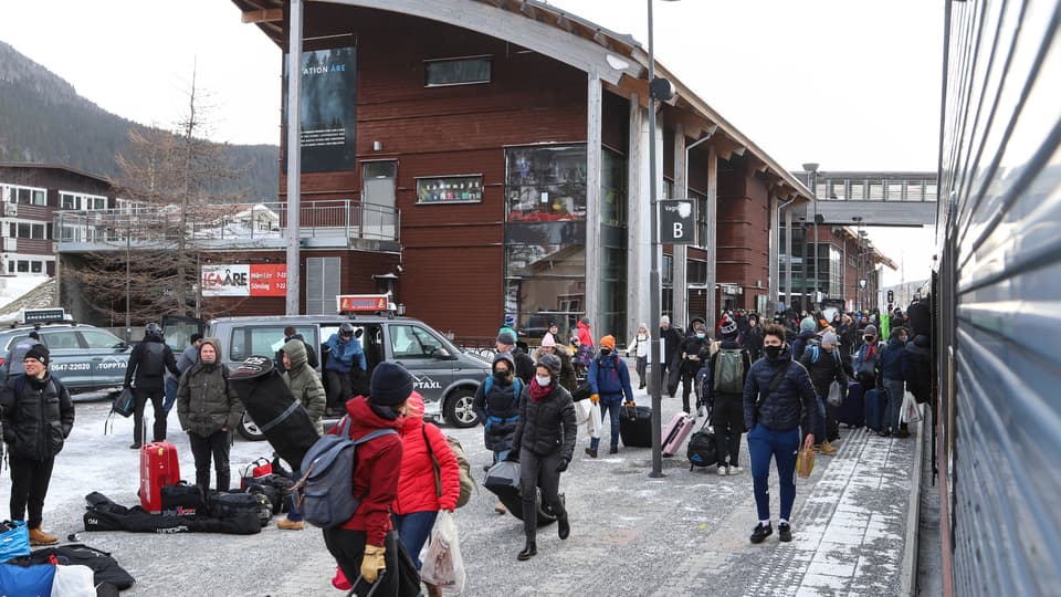 Turister utanför Åre Station, det är vinter och lite snö ligger kvar på marken.