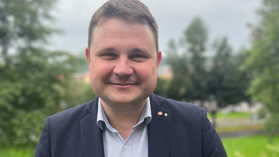 Porträttbild av leende mörkhårig man i mörk kavaj och grå skjorta