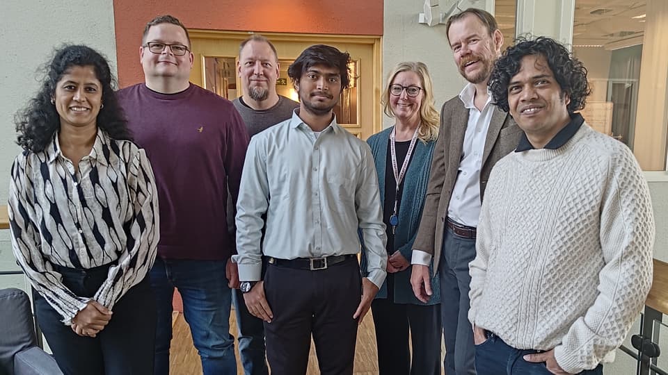 A group of people stand together and look into the camera.