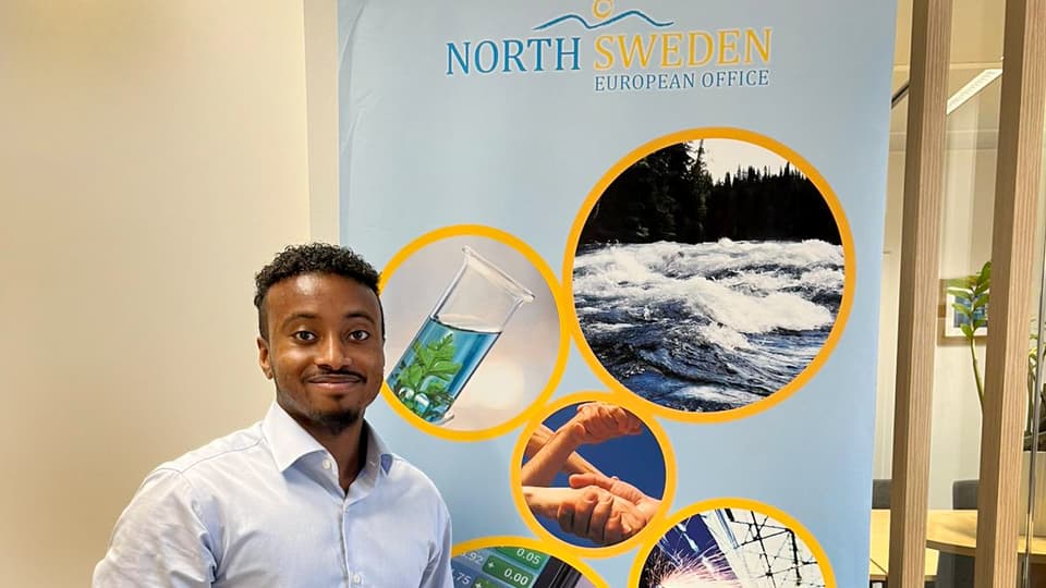 Man står framför en rollup som visar bilder av norra Sverige.