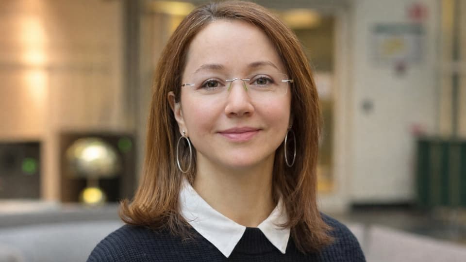 A woman looks into the camera and smiles.