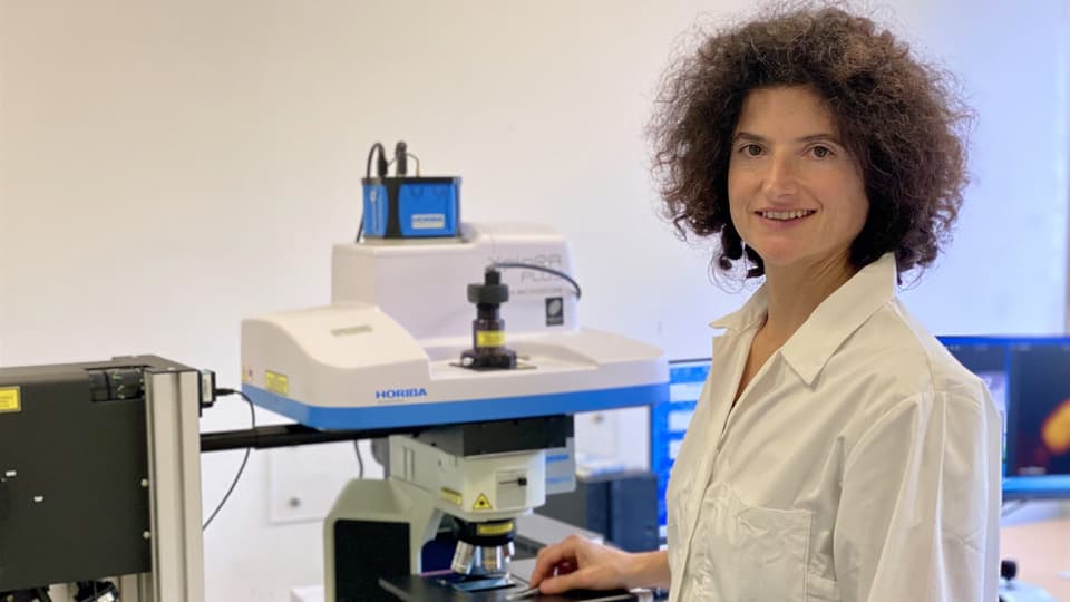  A woman in a laboratory setting smiles and looks into the camera.