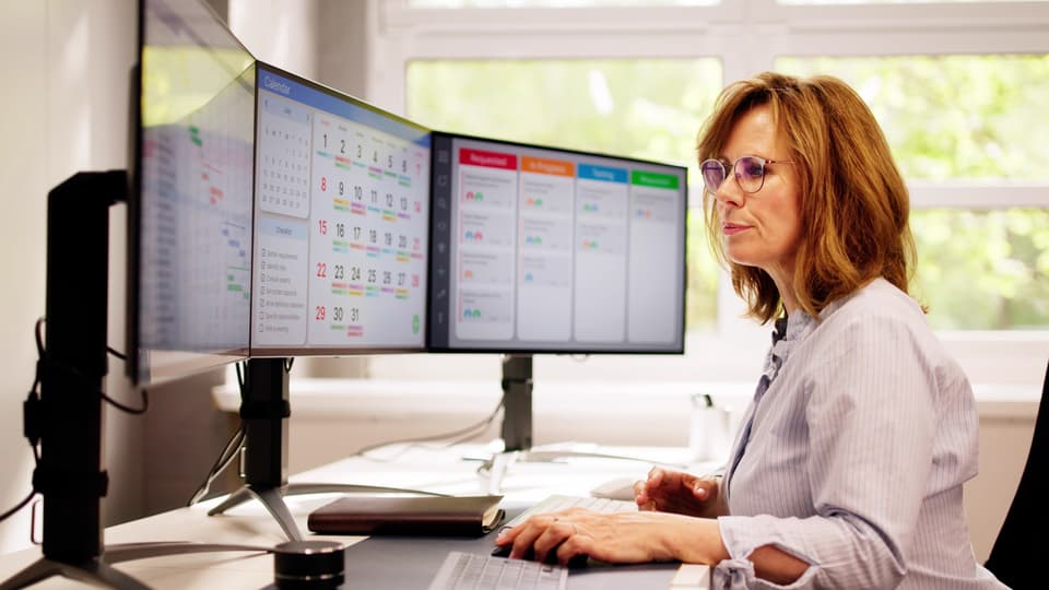 Woman working in front of computer screens