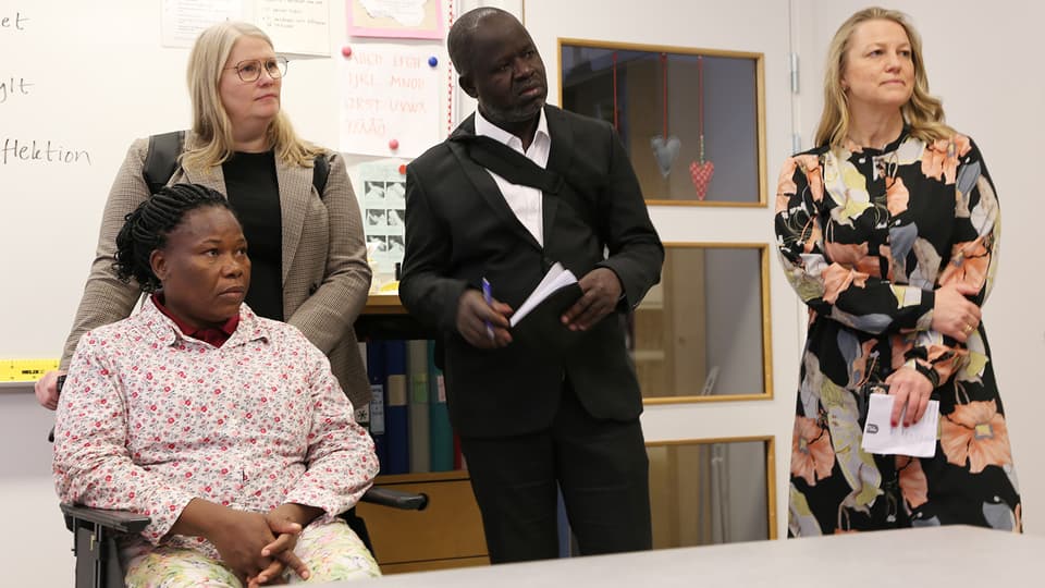 Four people listen interested in a classroom.