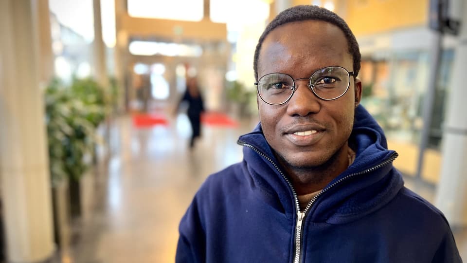 Man står inne i en ljushall, han har en blå huvtröja på sig.