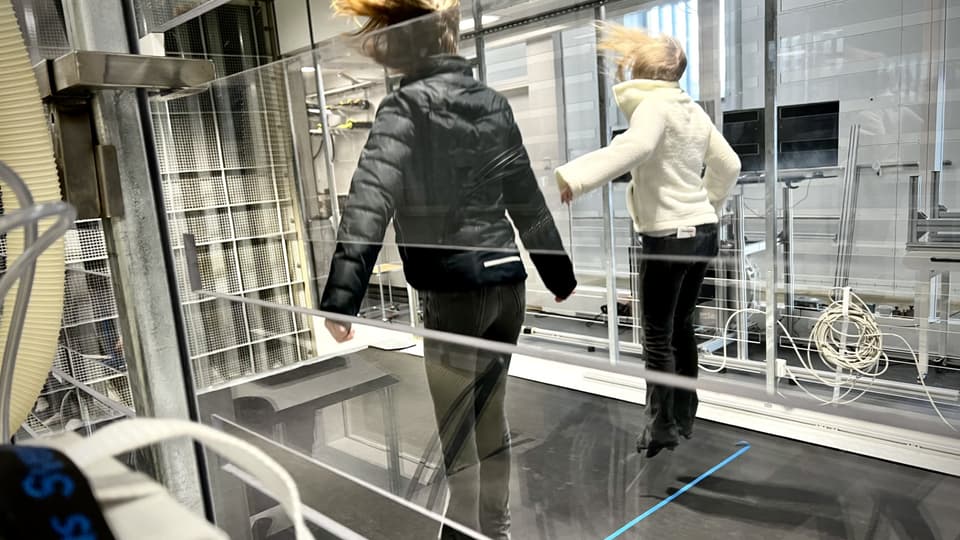 Två tjejer hoppar i samtidigt som det blåser väldigt mycket.