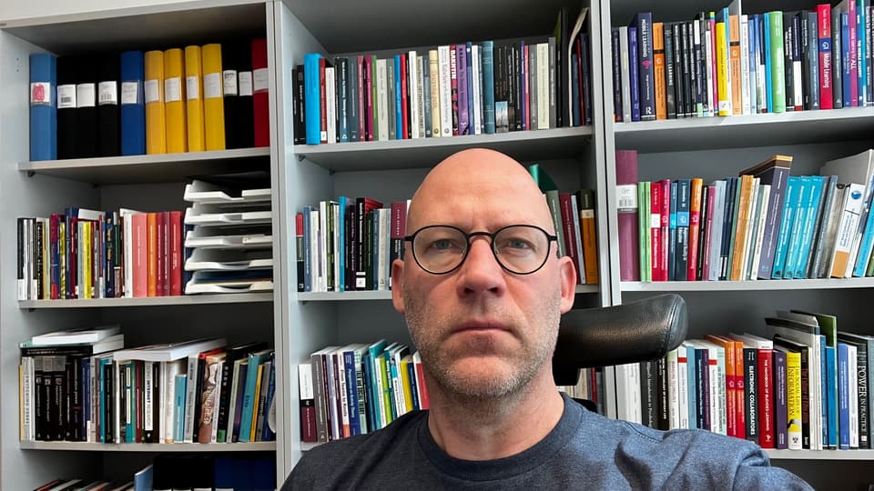 Jimmy Jaldemark framför en bokhylla med böcker