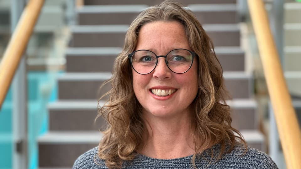 En kvinna med brunt hår och glasögon