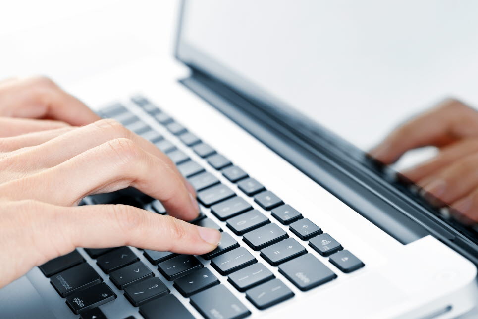 Hands typing on laptop keyboard